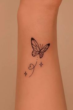 a small butterfly tattoo on the side of a woman's arm, with stars and hearts