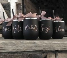 four black cups with pink bows are sitting on a mantle