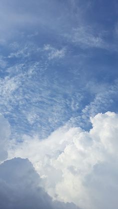 an airplane is flying high in the sky with white clouds behind it and blue skies above