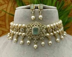 a necklace and earring set with pearls on a white mannequin neck piece