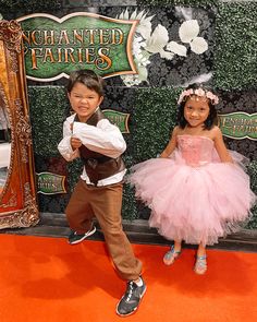 two young children dressed in fancy clothes posing for the camera on an orange carpeted area