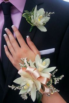 a man in a suit and tie with two boutonnieres on his lapel