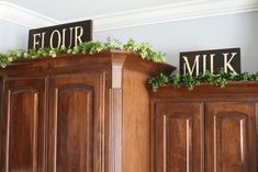 two signs that say flour and milk on top of wooden cabinets