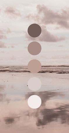 four circles are arranged in the shape of five different colors on a beach with water and clouds