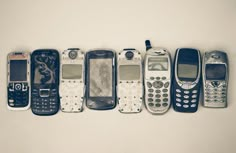 an array of old cell phones lined up in a row on a white background with space for text