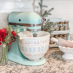 a blue mixer sitting on top of a counter next to a bowl filled with flowers