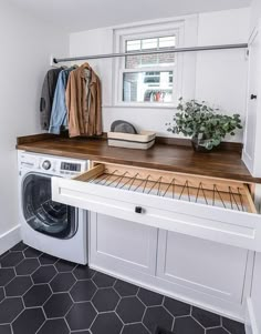 a washer and dryer in a white laundry room with black tile flooring