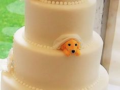 a three tiered wedding cake with an orange dog on the top and white frosting