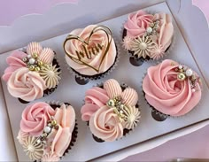 cupcakes decorated with pink and white frosting in a box