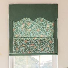 a window with a green roman blind in front of it and flowers on the valance