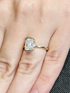 a woman's hand with a diamond ring on top of her finger and an engagement band