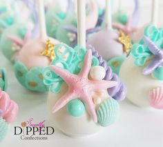 the cake pops are decorated in pastel blue, pink and green with seashells on them