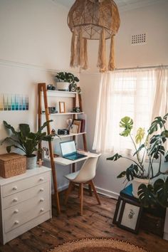 a room with a desk, shelves and plants in it that are hanging from the ceiling