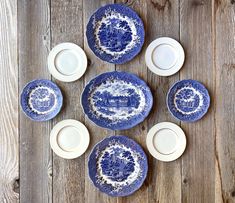 six blue and white plates sitting on top of a wooden table