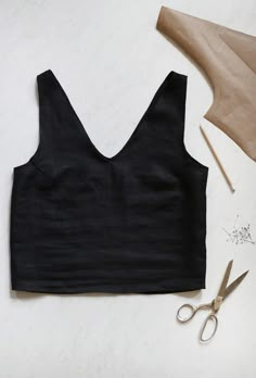 a black crop top next to some scissors and other crafting supplies on a white surface