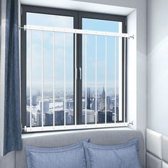 a bed with blue sheets and pillows in front of a window overlooking the cityscape