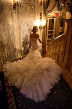 a woman in a wedding dress is walking down the stairs