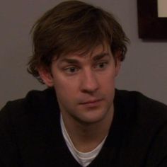 a young man is looking at the camera while wearing a black sweater and white t - shirt