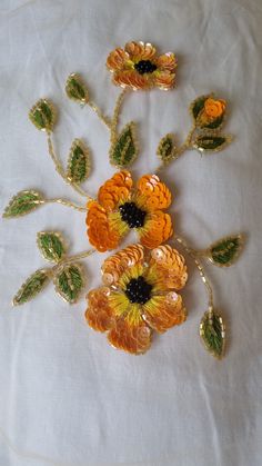 an orange and yellow flower brooch sitting on top of a white cloth