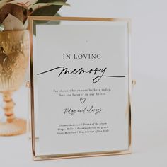 a wedding card with the words in loving memory on it next to a gold vase