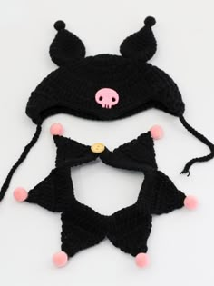 two knitted hats with pink and black pom poms on the top one has a skull in the middle