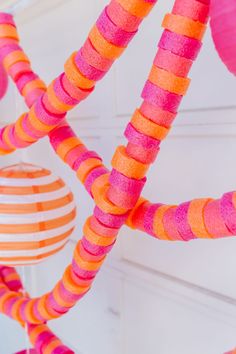 some pink and orange streamers hanging from the ceiling in front of a white wall