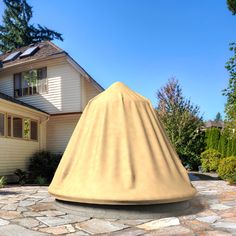 a large beige cone sitting on top of a stone walkway next to a white house