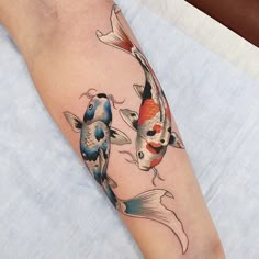 a woman's leg with two koi fish tattoos on it