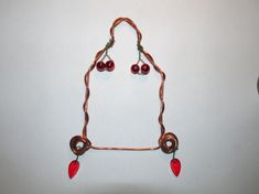 a piece of art made out of copper wire with red beads hanging from it's sides