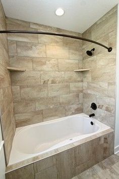 a bath tub sitting under a window next to a shower head mounted faucet