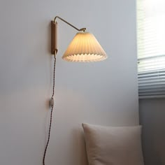 a lamp that is on the wall next to a pillow