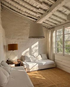 a bed room with two beds and a lamp hanging from the ceiling in front of a window