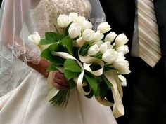 the bride and groom are walking down the aisle holding their wedding bouquet in each other's hands