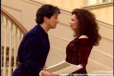 a man and woman standing next to each other in front of a stair case holding papers