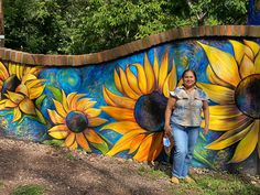 a man and woman standing in front of a painted sunflower mural on the side of a building