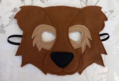 a brown bear mask with eyes and nose on top of a white wallpapered surface