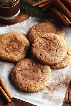 three cookies on top of a piece of paper next to cinnamon sticks