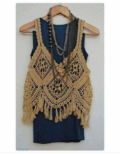 a crocheted vest with chains and beads hanging on a hanger in front of a white wall