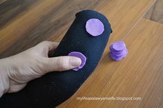 a hand is holding an object that looks like a roll of black material with purple felt on it