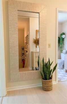 a potted plant sitting on the floor in front of a mirror that is next to a toilet