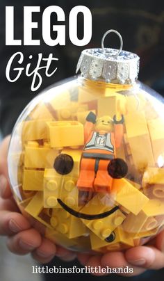 someone holding a lego ornament in their hand with the words lego gift on it