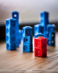 blue and red legos sitting on top of a wooden table next to each other