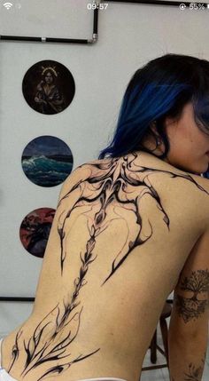 a woman with blue hair and tattoos on her back