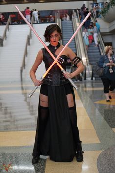 a woman dressed as darth vader holding two swords