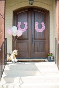 a dog sitting in front of a door with balloons