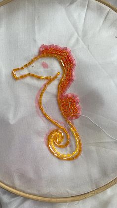 an embroidery project with a sea horse on it's back and yellow thread in the middle