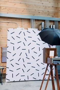 an umbrella is placed on a tripod in front of a wall with arrows drawn on it