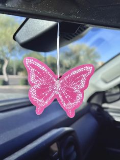 a pink butterfly hanging from the dashboard of a car