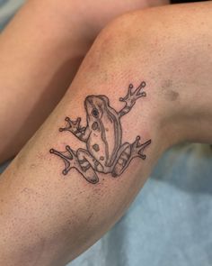 a frog tattoo on the leg of a woman's legs, which is covered in black ink