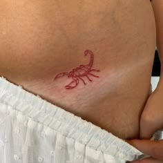 a woman's stomach with a red scorpion tattoo on it